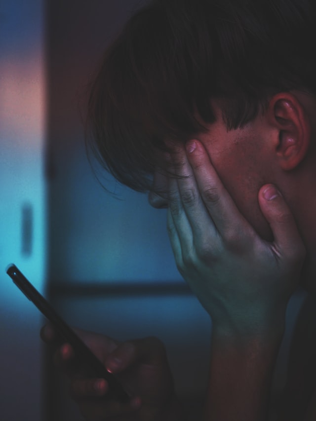 young man looking at his phone in a dark toom